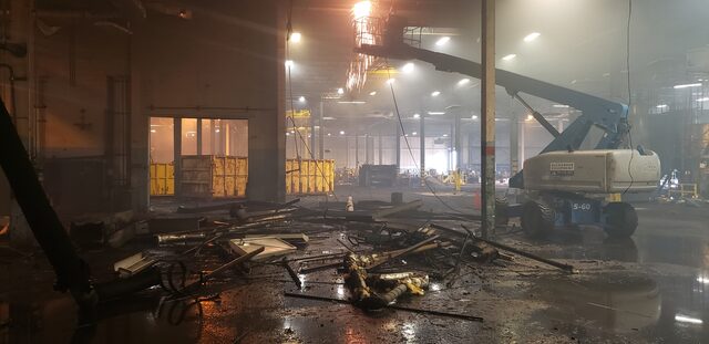Cutting overhead steel from a boom lift, the plant floor already stripped and stacked with scrap