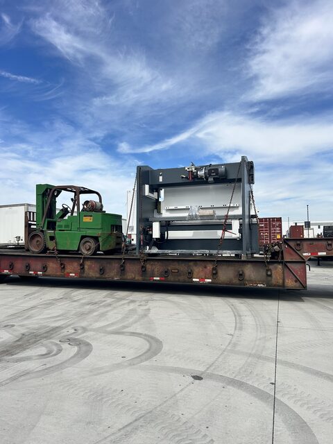 A press brake chained to the lowboy with our forklift riding along beside it