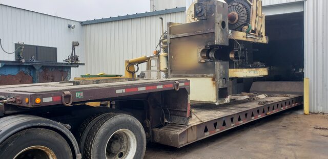 A press section sitting on the lowboy outside the plant door, ready to roll
