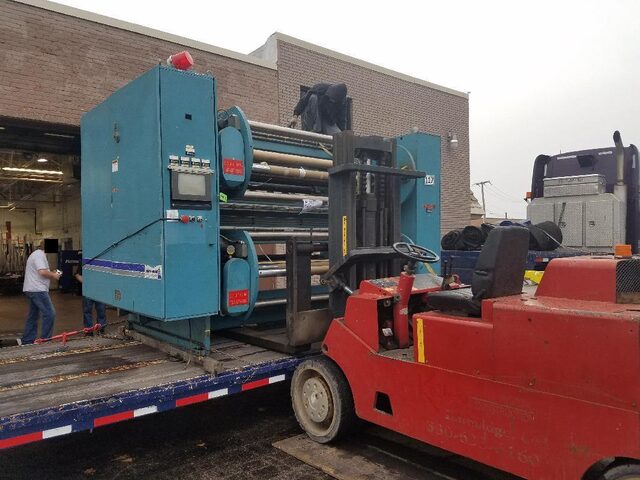 A roll-coating machine coming out to the trailer at the dock, heavy forklift doing the carrying