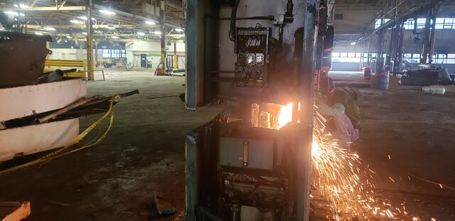 Sparks running off the torch as a machine base is cut down for hauling