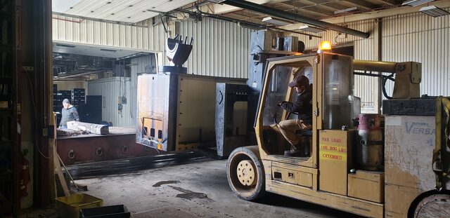 Our 60-80,000 lb Versa-Lift carrying a machine base out through the shop door