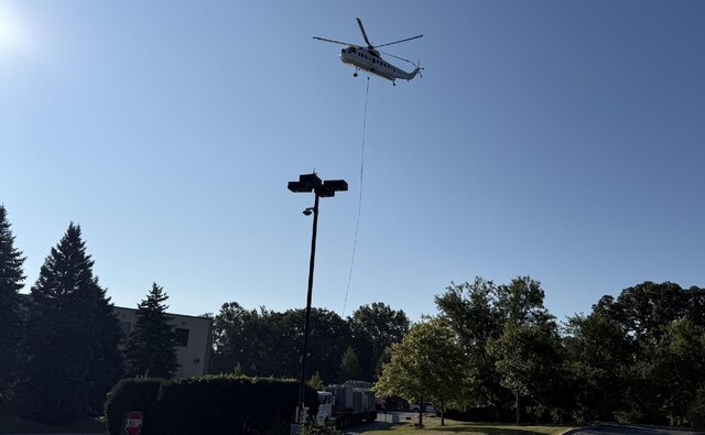 A heavy lift helicopter on a long line, setting rooftop condensing units onto our truck