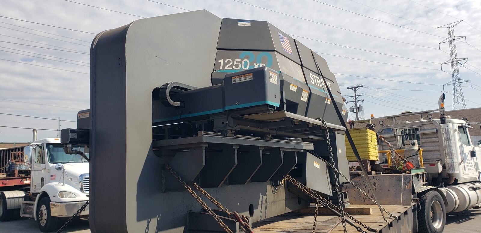 A Strippit 1250 XP/30 CNC turret punch press chained down on our step deck trailer