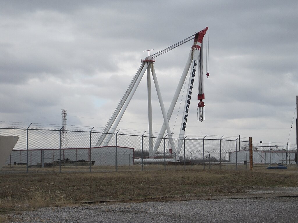 A Barnhart ring crane towering over their Memphis yard with wind turbine blades on the ground; this is the scale of iron the national heavy lift companies bring