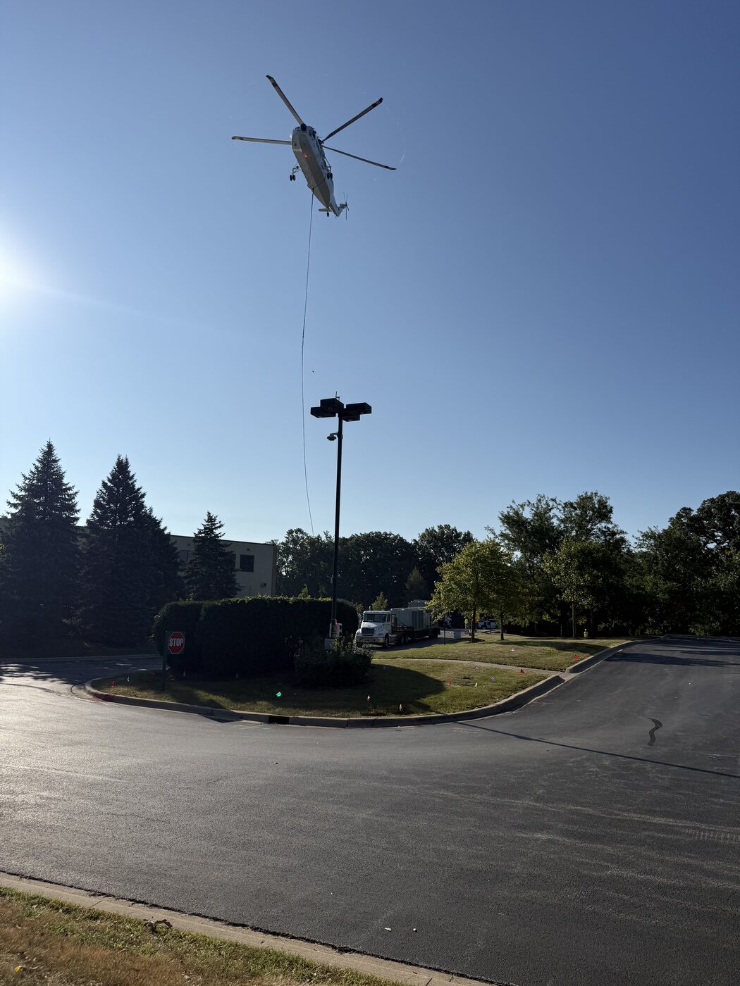 The closed parking lot serving as the landing zone early in the morning, empty of cars, with the helicopter working overhead