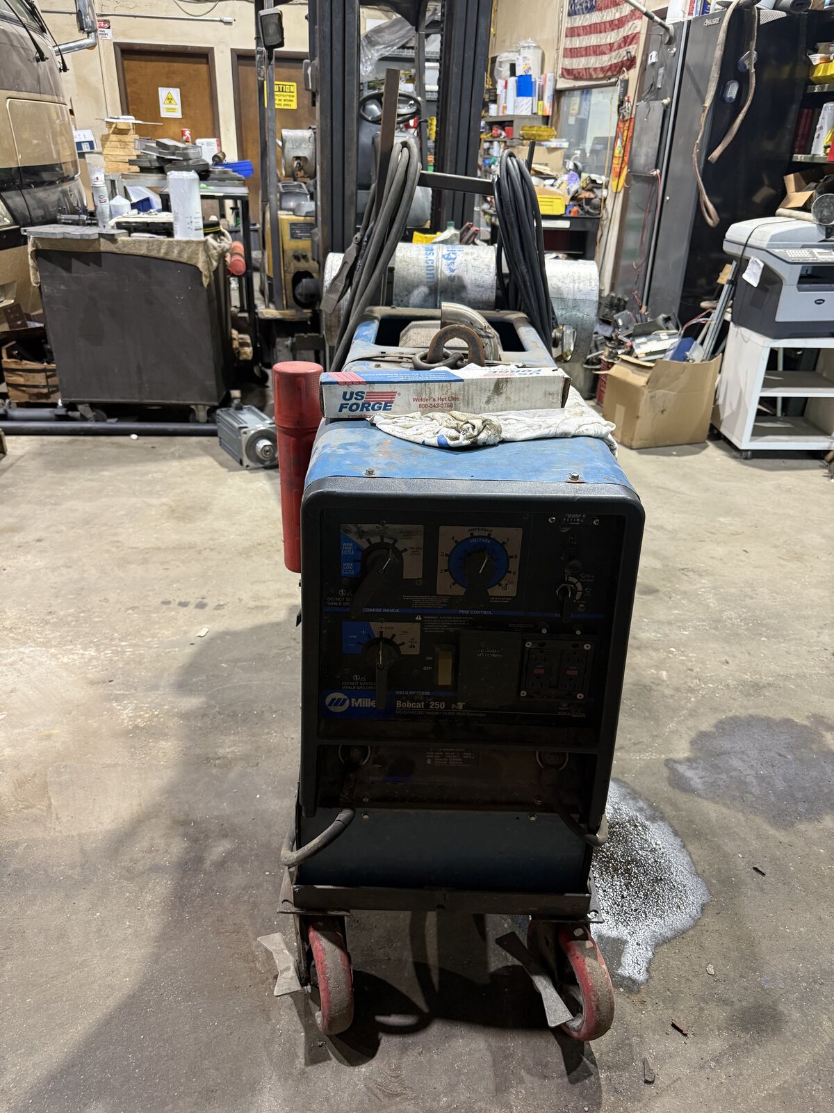The Miller Bobcat 250 engine-driven welder on its wheels in the shop, ready to go on the truck