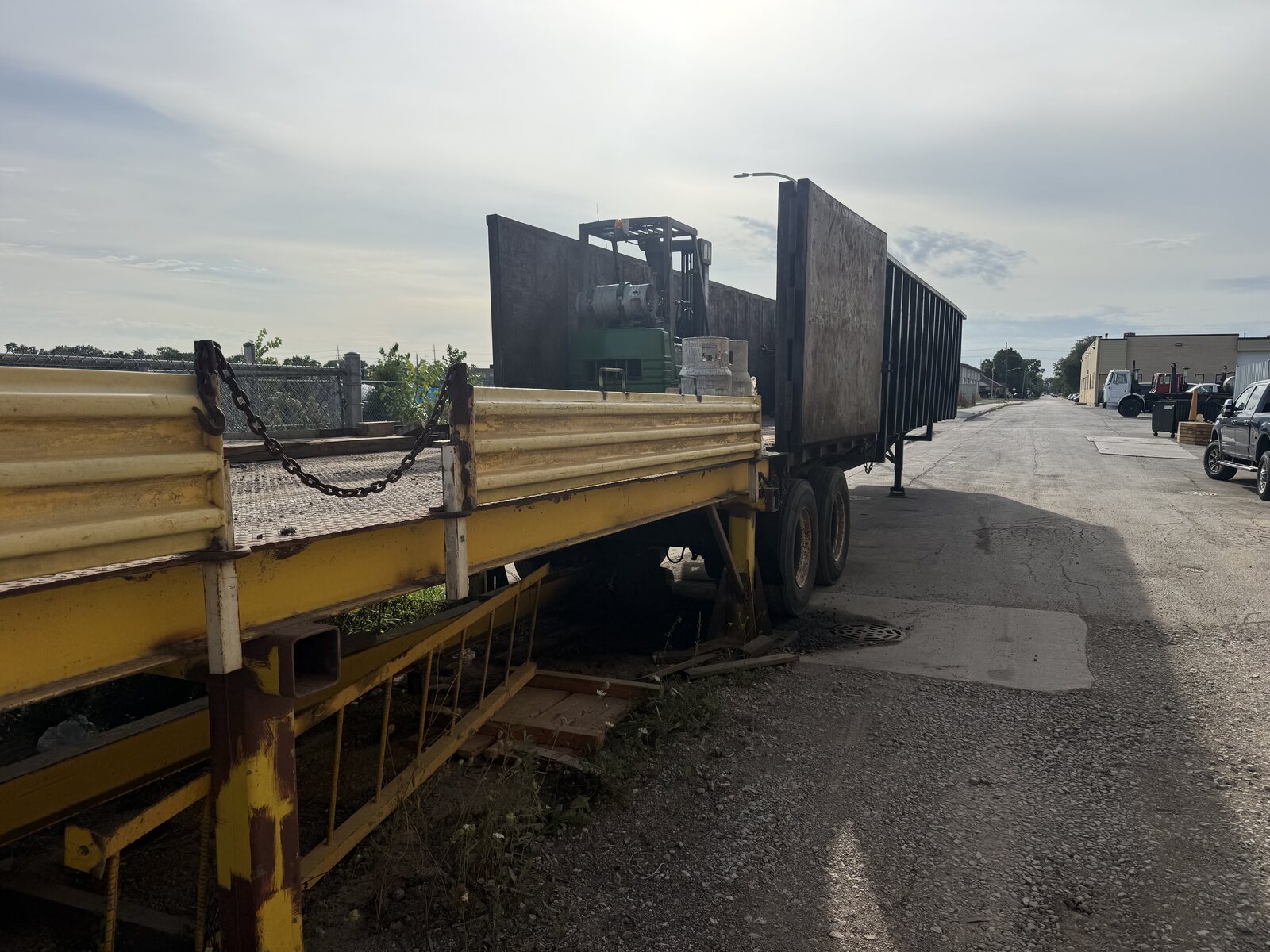 The gondola trailer backed against the yellow rail of the platform, with the forklift visible inside the gondola
