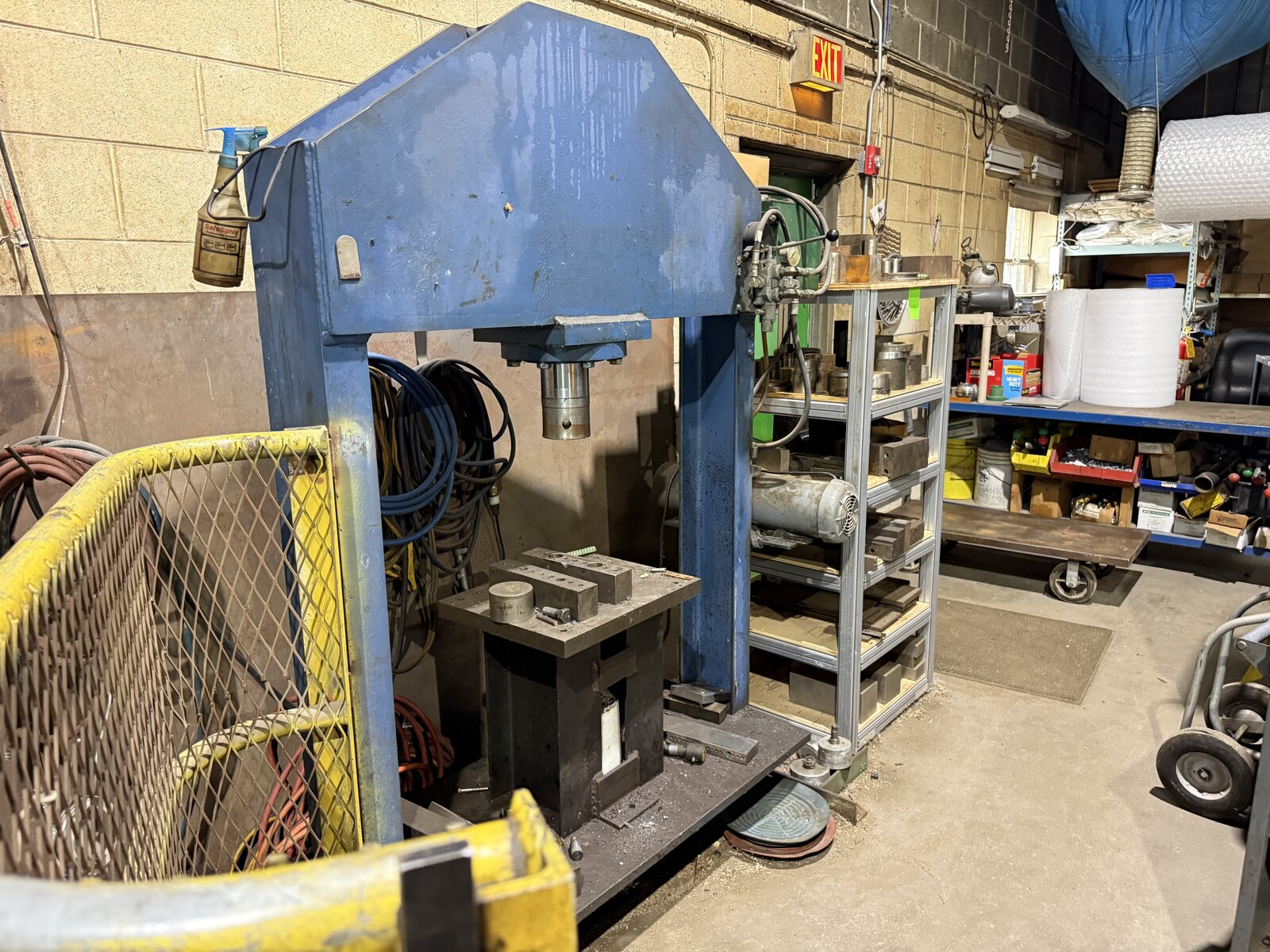 The blue hydraulic shop press with its safety cage