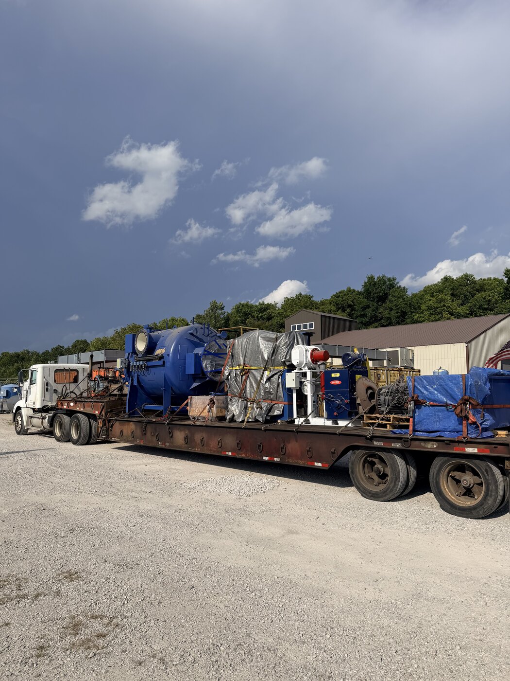 The loaded lowboy in front of the Indiana building: furnace chamber, control cabinet, tarped and strapped pieces, ready for the road