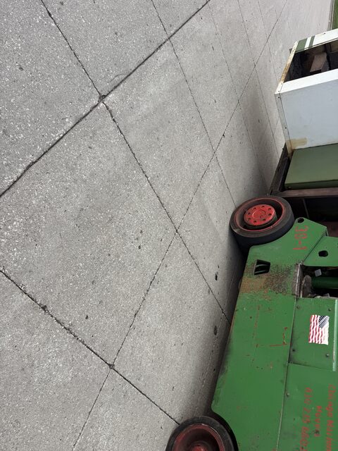 Our forklift carrying the machine along a street past a brick building