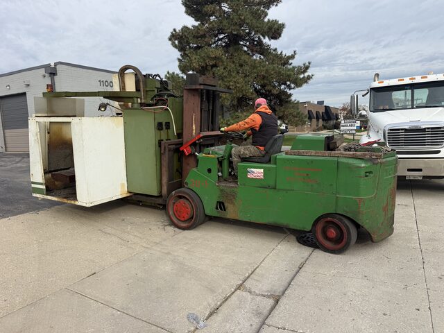 Our forklift and the machine outside a shop building, with a white tractor parked behind