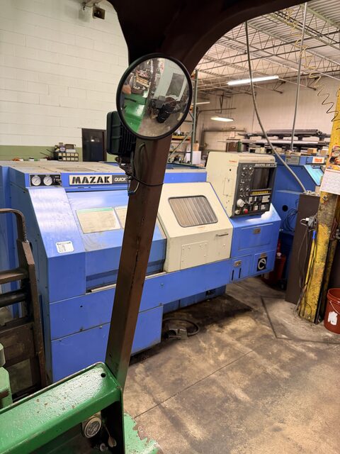 A blue Mazak lathe seen from the forklift operator's seat