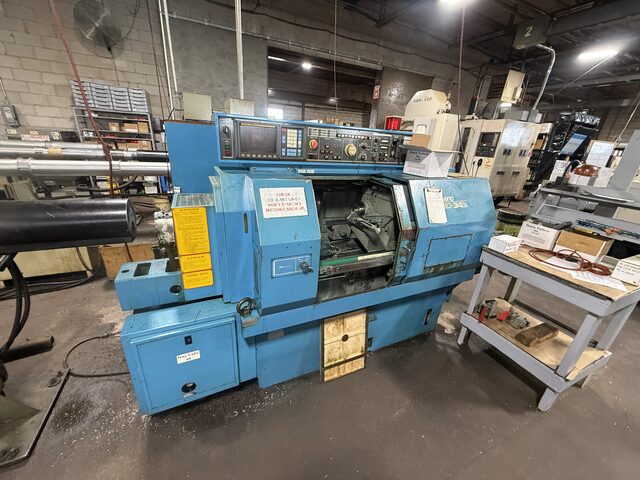 A blue CNC lathe beside a work table