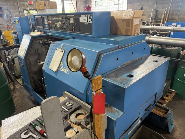 A blue CNC lathe, with a red tag hanging from a post in front of it