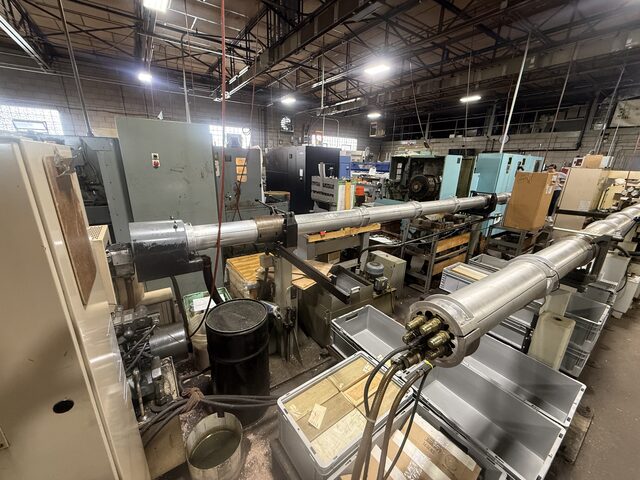 CNC lathes with long bar feeders, in a row along a shop aisle