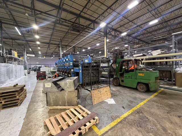 The forklift at the end of the press line, with steel parts on pallets in the foreground