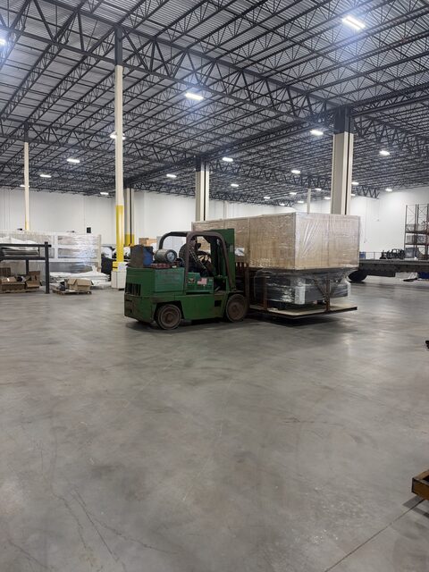 Our forklift carrying a crated section of an HSG laser machine across the warehouse floor