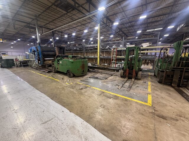 Three green forklifts beside the press unit